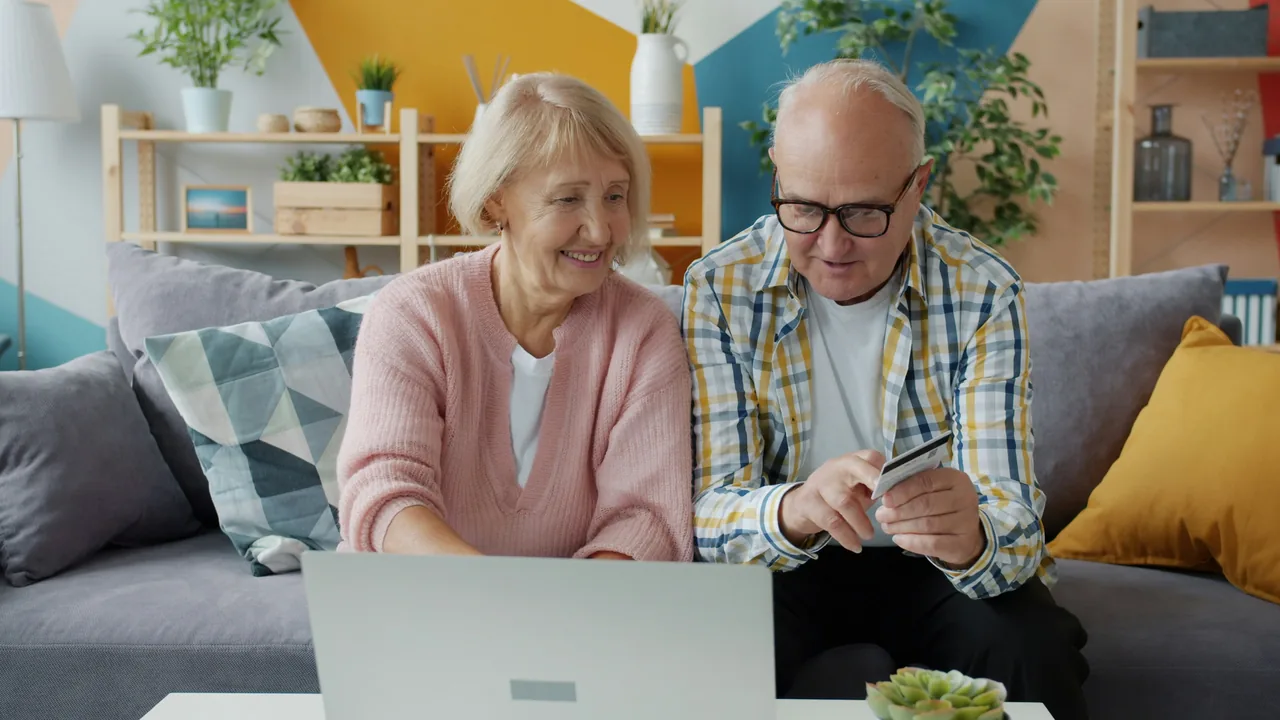 Older couple using a laptop and holding a credit card at home